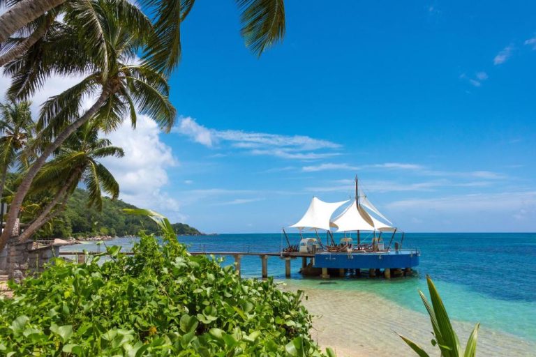 Muelle sobre el mar con carpa blanca del Coco de Mer Hotel and Black Parrot Suites en Seychelles