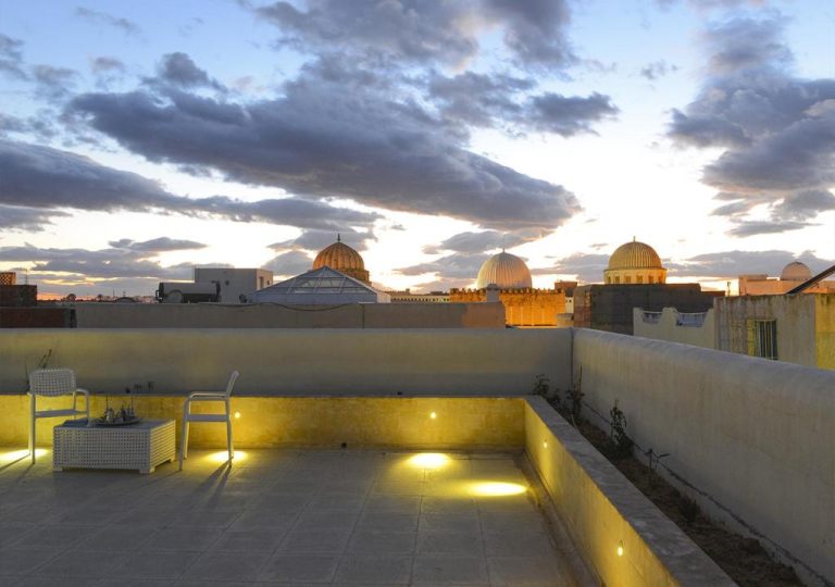 Terraza iluminada del Dar Alouini con vistas panorámicas a las cúpulas de la mezquita al atardecer