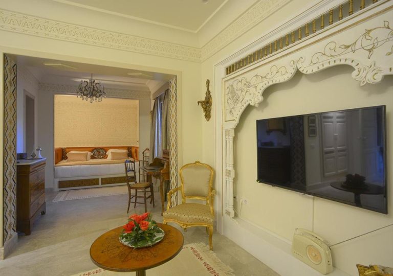 Salón de suite con decoración árabe clásica, molduras doradas y TV en Dar Alouini
