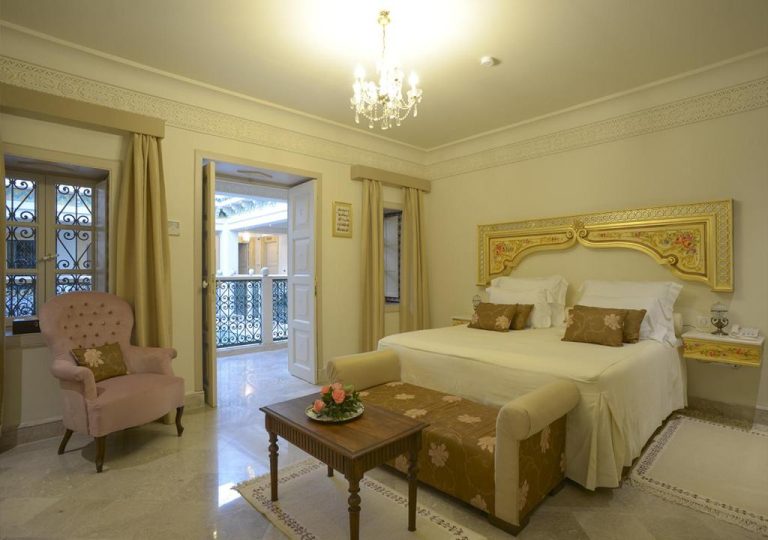 Habitación doble de lujo con cabecero dorado y lámpara de araña en el hotel Dar Alouini