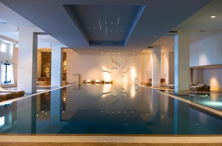 Piscina interior climatizada con zona de relax y decoración elegante en el spa del Hotel Excelsior