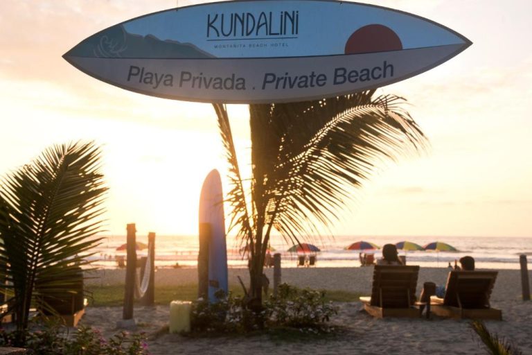 Playa privada del Hotel Kundalini Montañita al atardecer con tabla de surf y palmeras