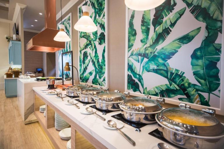 Estación de buffet con fuentes de comida caliente y decoración tropical en Hotel Oro Verde Guayaquil