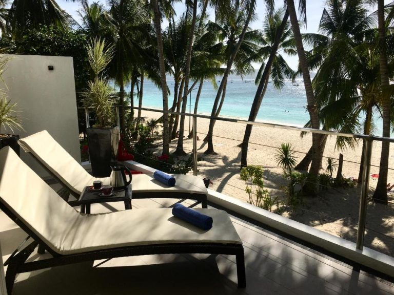 Terraza con tumbonas y vista a la playa de arena blanca en Sundown Beach Studios Boracay