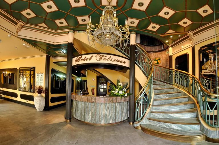 Recepción principal con escalera de mármol y lámpara de araña del Hotel Talisman