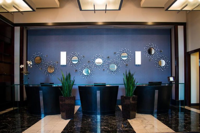 Recepción moderna del Platinum Hotel con espejos decorativos en pared azul y plantas ornamentales
