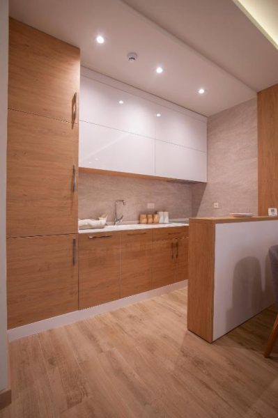 Cocina equipada con armarios de madera y encimera blanca en el Hotel Vela