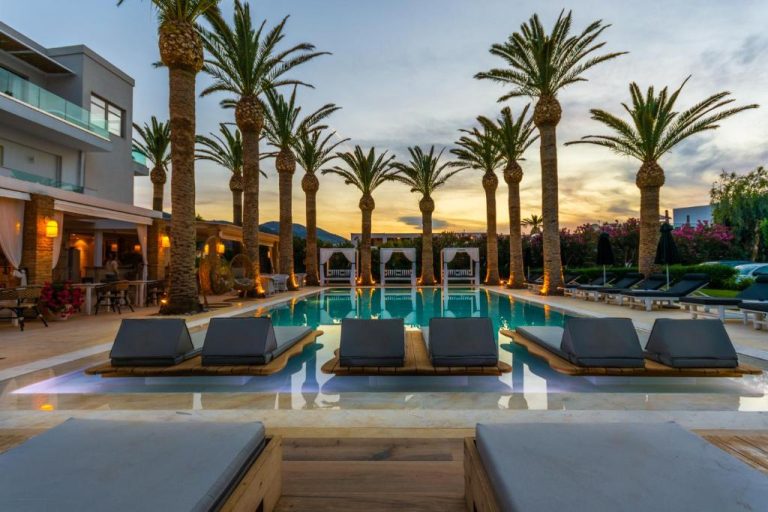 Piscina exterior con tumbonas y palmeras al atardecer en Drossia Palms Hotel and Nisos Beach Suites