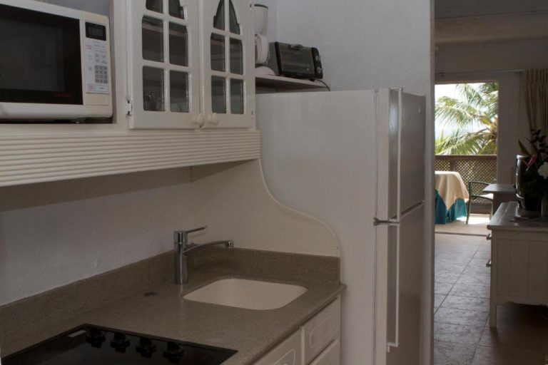 Cocina equipada con microondas, nevera, fregadero y vitrocerámica en Tropical Sunset Beach Apartment Hotel