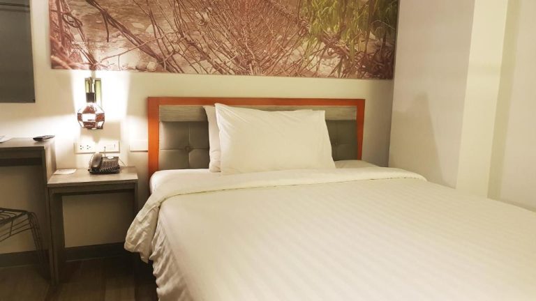 Habitación con cama doble y cabecero en madera del Hotel GQ Plaza con decoración moderna