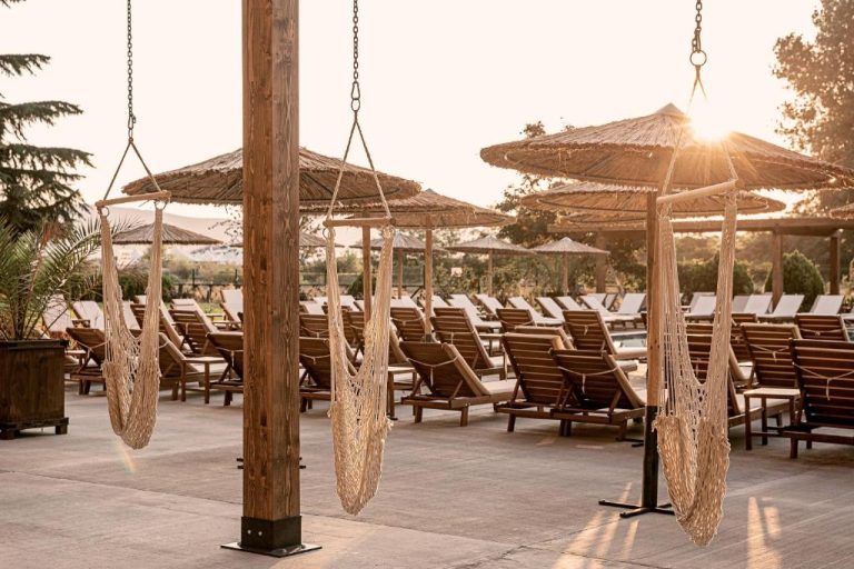 Zona de piscina con tumbonas de madera y hamacas colgantes al atardecer en Sunny Beach Club Adults Only