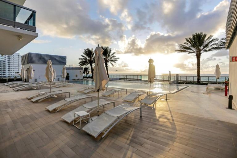 Piscina exterior con tumbonas y vistas al mar al atardecer en Monte Carlo by Miami Vacations