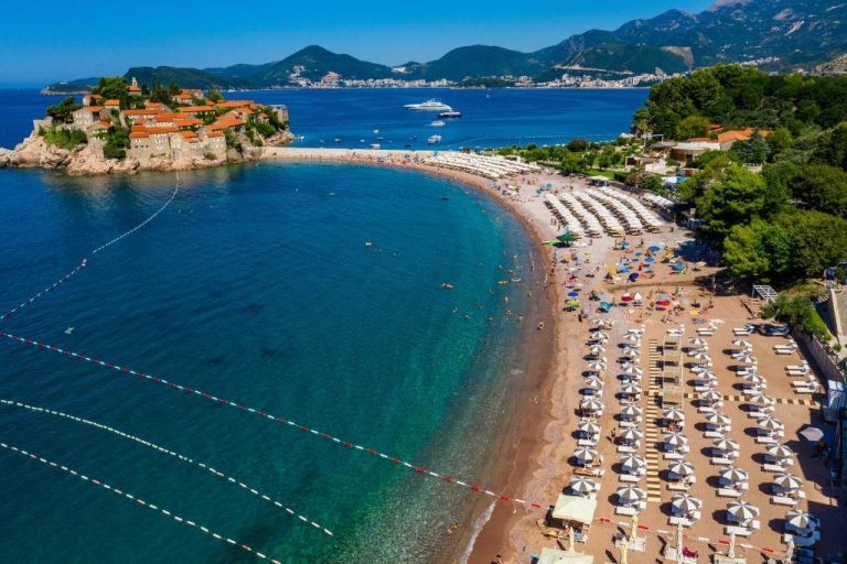 Vista aérea de la playa de Sveti Stefan con tumbonas y sombrillas junto al Hotel California by Aycon