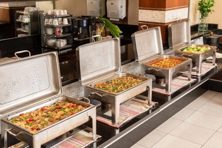 Buffet de almuerzo con bandejas calientes y variedad de platos en el restaurante del Intercity Florianopolis