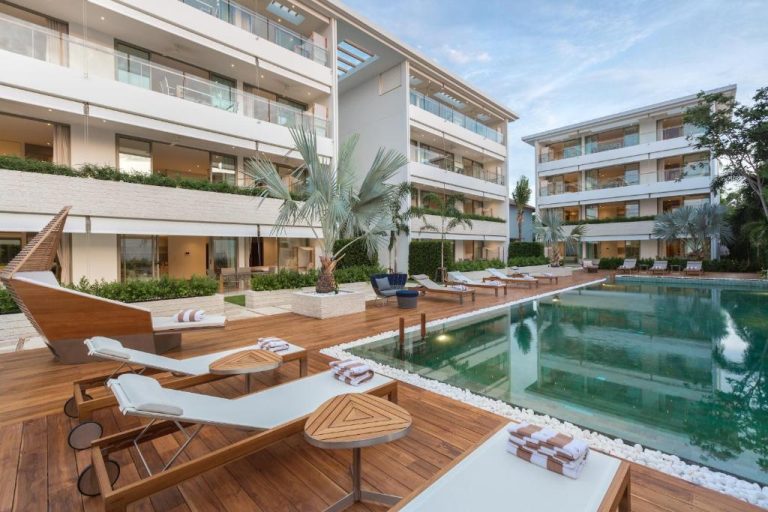 Piscina exterior con tumbonas y terraza de madera del hotel Chi The Residence rodeada de edificios modernos
