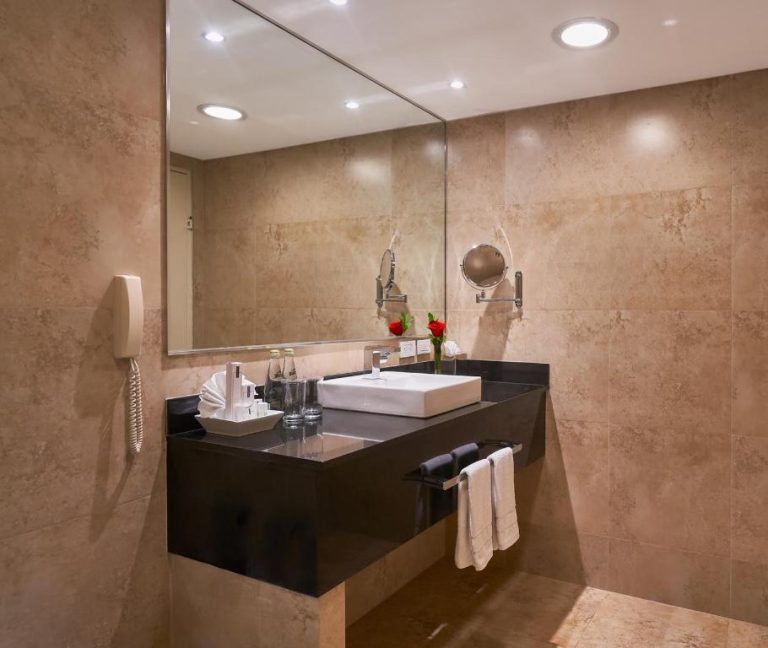 Baño de lujo con encimera negra y lavabo blanco en el Hotel Oro Verde Guayaquil