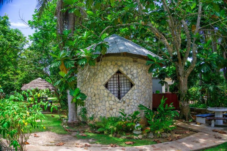 Cabaña circular de piedra con techo de metal rodeada de vegetación tropical en Yoga Dreams Negril Jamaica
