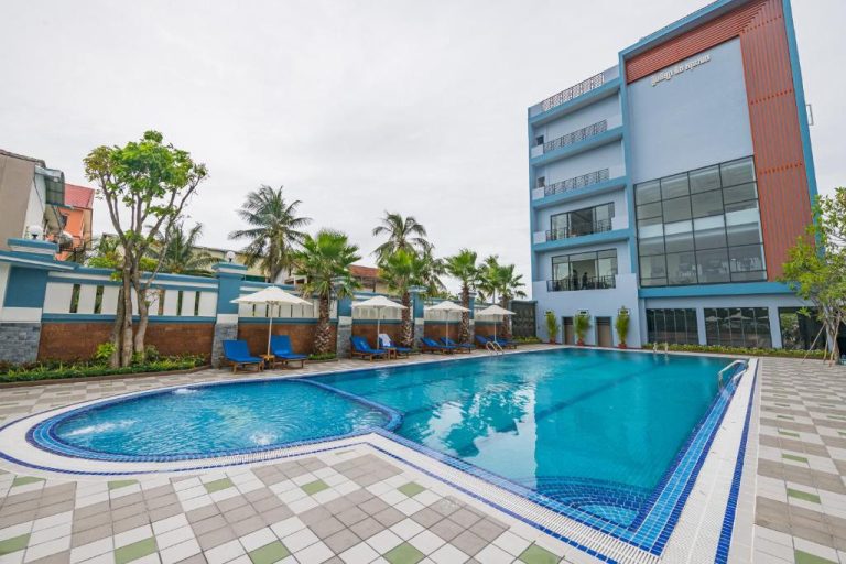 Piscina exterior con tumbonas azules y palmeras del Kampong Thom Royal Hotel en Camboya