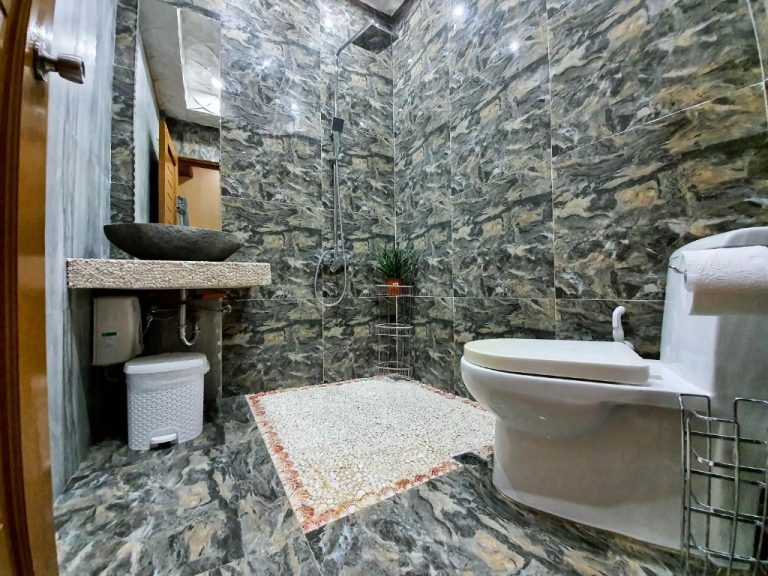 Baño privado con paredes de mármol, ducha y sanitarios del Kaiyana Boracay Beach Resort