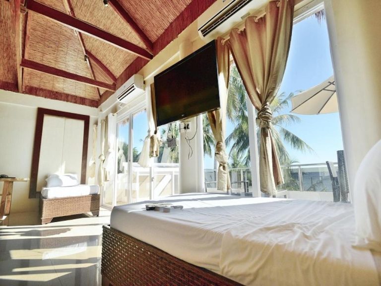 Habitación con cama doble, TV y vista panorámica a palmeras y playa en Kaiyana Boracay Beach Resort