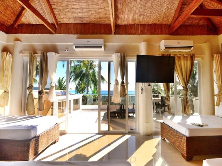 Habitación con techo de paja y vistas al mar en Kaiyana Boracay Beach Resort con camas y TV