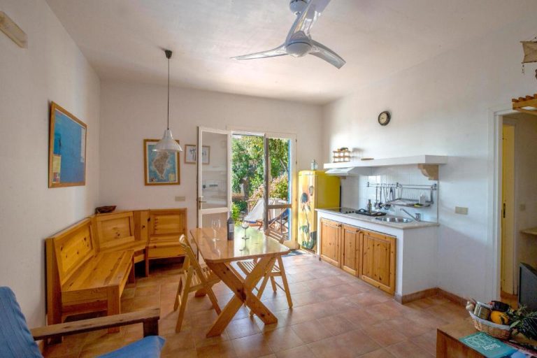 Cocina americana y salón comedor con muebles de madera en Marettimo Residence con acceso a jardín