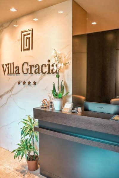 Recepción elegante con mármol y flores del Hotel Villa Gracia, establecimiento de cuatro estrellas