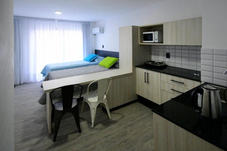 Estudio con cocina equipada, mesa comedor y cama doble en Quijano Hotel Aparts and Suites