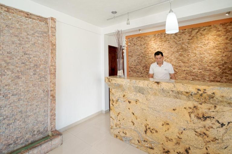 Recepción con mostrador de mármol y paredes de piedra natural en Hotel Yumkiin cerca del Ferry