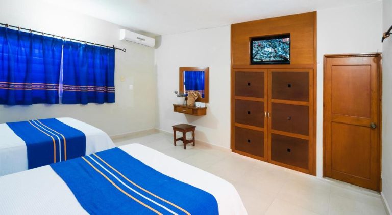 Habitación doble con dos camas, televisión y armario de madera en Hotel Yumkiin cerca del Ferry