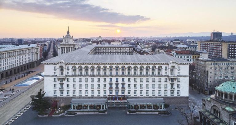 Vista aérea de la imponente fachada exterior del Sofia Balkan Palace al atardecer en el centro de Sofía