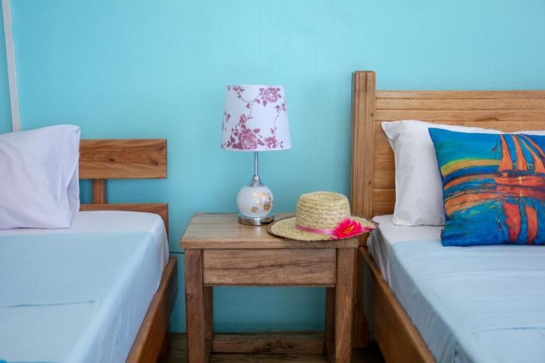 Habitación doble con dos camas de madera y decoración tropical en Villa Paradise Rodrigues