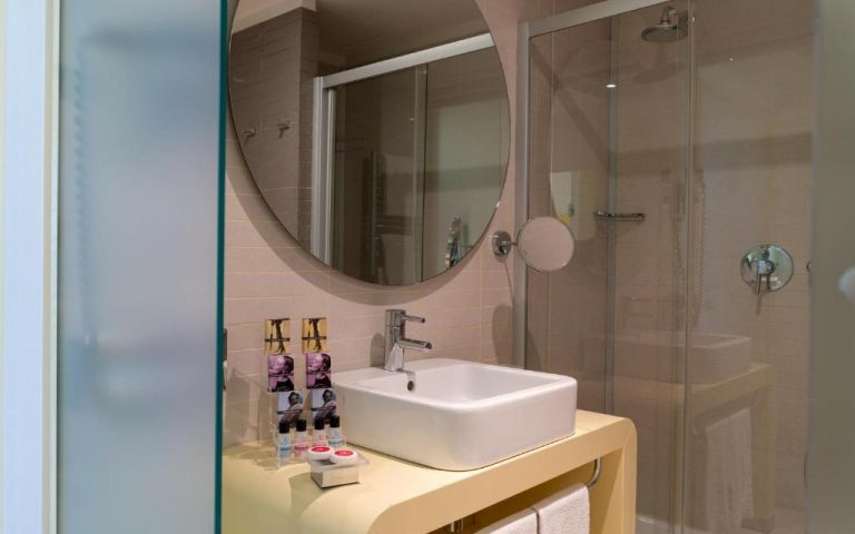 Baño moderno con ducha de cristal y lavabo del hotel Domina Zagarella Sicily en Sicilia