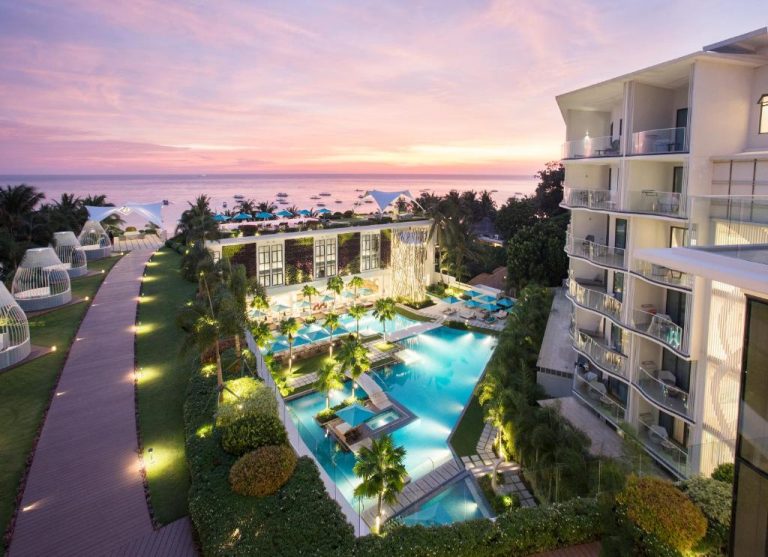 Piscina exterior iluminada con vistas al mar al atardecer en The Lind Boracay, Filipinas