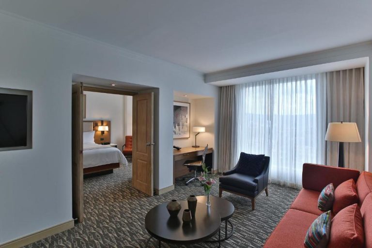 Suite con sala de estar, sofá rojo y dormitorio separado en InterContinental Tegucigalpa at Multiplaza Mall