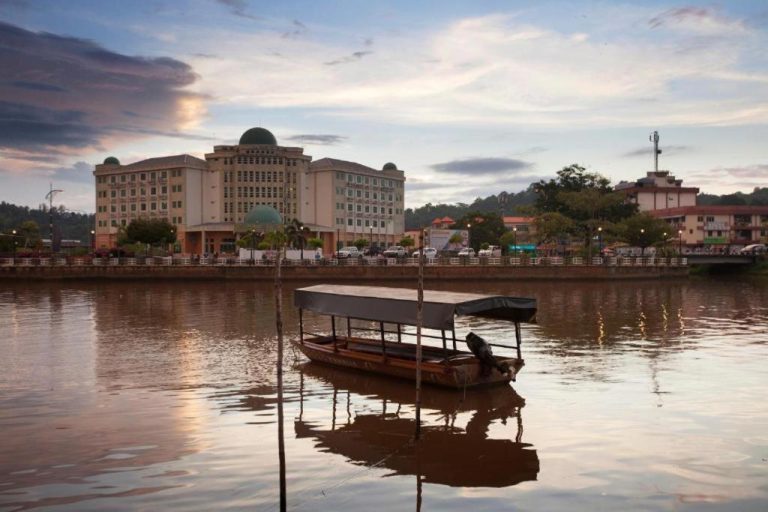 Vista del Hotel Seri Malaysia Lawas desde el río Lawas al atardecer con barca tradicional