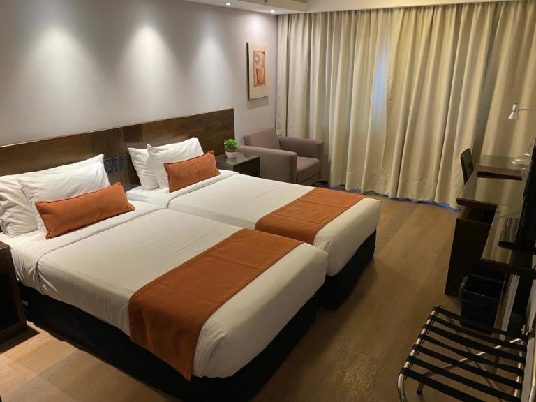 Habitación doble twin con camas individuales y decoración en tonos naranja del Hotel Crystal Tower