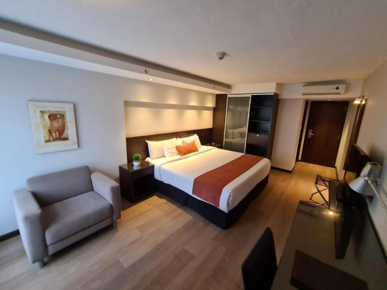 Habitación doble con cama king size y sillón en el Hotel Crystal Tower, decoración moderna