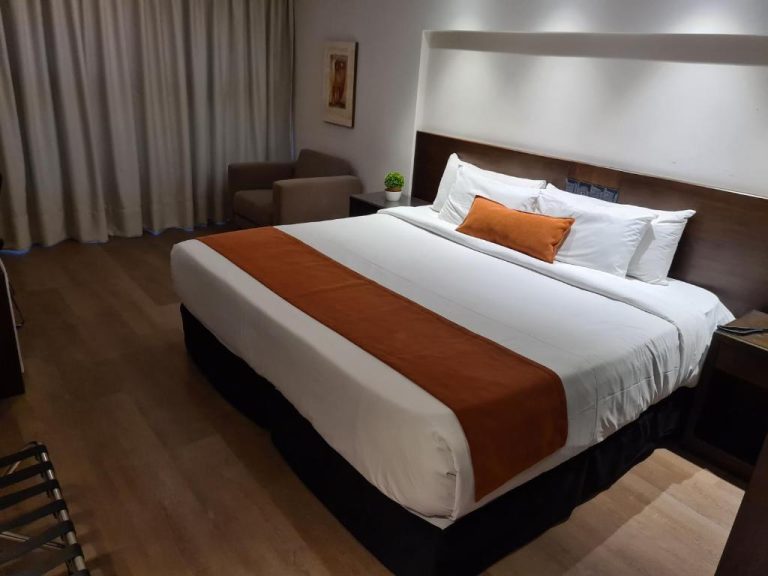 Habitación doble king size con cama grande y decoración en tonos naranja y blanco en Hotel Crystal Tower