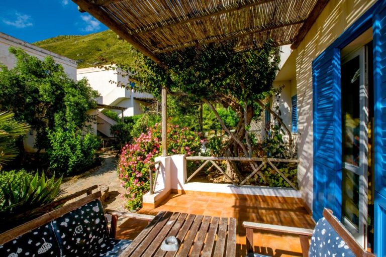 Terraza con pérgola de madera y jardín con flores del Marettimo Residence en Sicilia