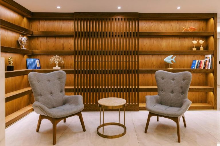 Sala de lectura con sillones grises y estantería de madera en el Acandia Hotel