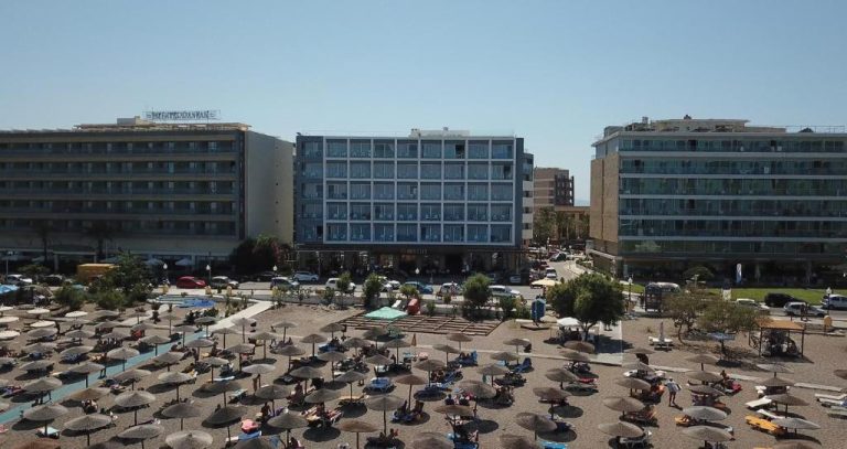 Vista aérea del Ibiscus Hotel con playa de sombrillas y tumbonas en primera línea de mar