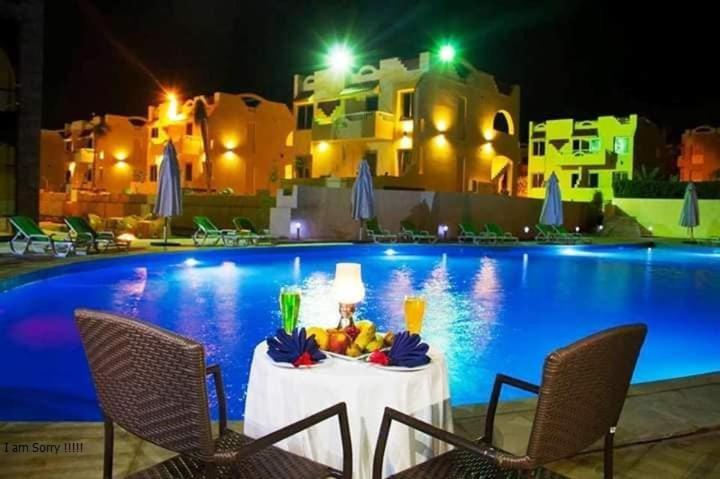 Piscina iluminada de noche con mesa romántica y cócteles en el Green Leaves Hotel