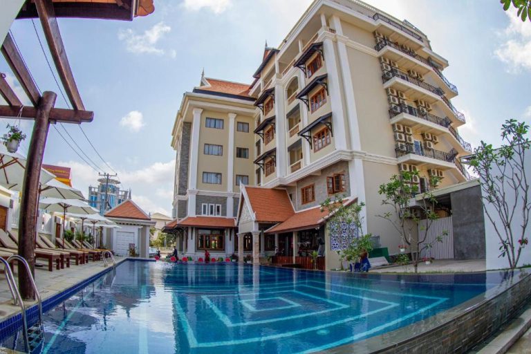 Piscina exterior con tumbonas y sombrillas del Kampong Thom Palace Hotel con vistas al edificio principal