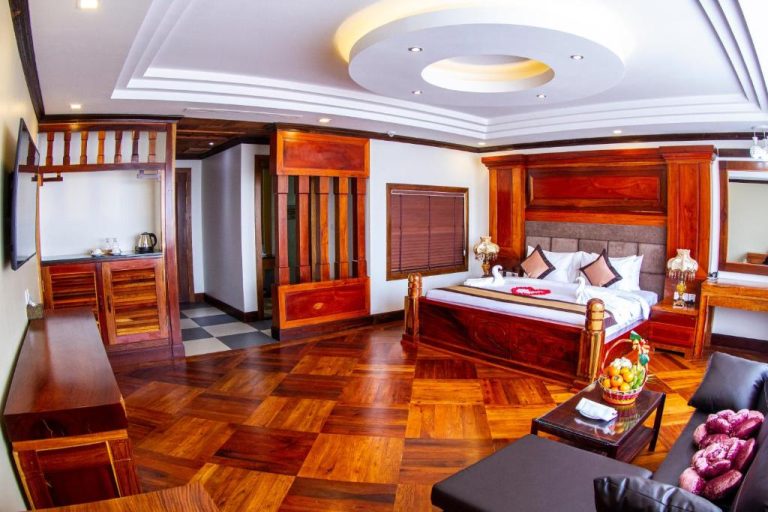 Suite de lujo con cama doble y mobiliario de madera en Kampong Thom Palace Hotel