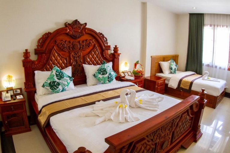 Habitación deluxe con cama de madera tallada artesanal en el Kampong Thom Palace Hotel