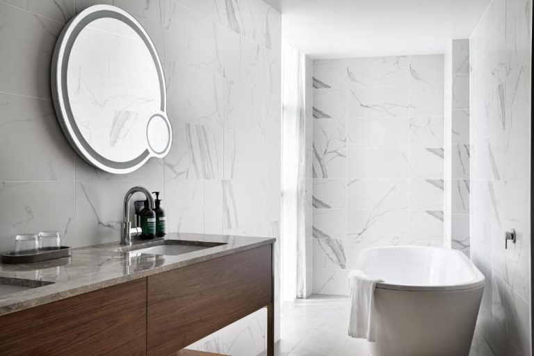 Baño de lujo con bañera exenta y revestimiento de mármol blanco en Crowne Plaza Sydney Darling Harbour