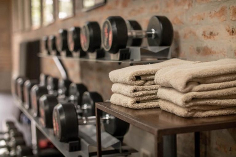 Sala de gimnasio del Factoria Hotel con mancuernas en rack y toallas disponibles para los huéspedes