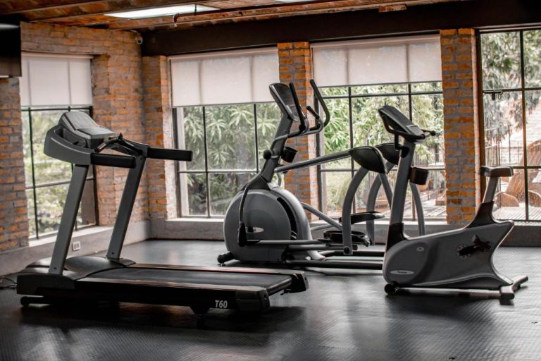 Gimnasio del Factoria Hotel con cinta de correr T60, elípticas y bicicleta estática junto a ventanales