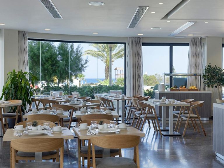 Restaurante con mesas y sillas de madera y vistas al mar en Cactus Hotel Adults Only 21 Plus